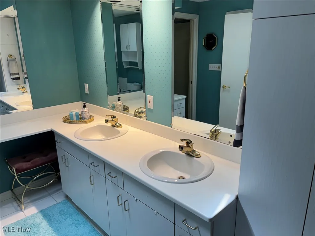 Full bathroom with double vanity, tile patterned floors, and toilet