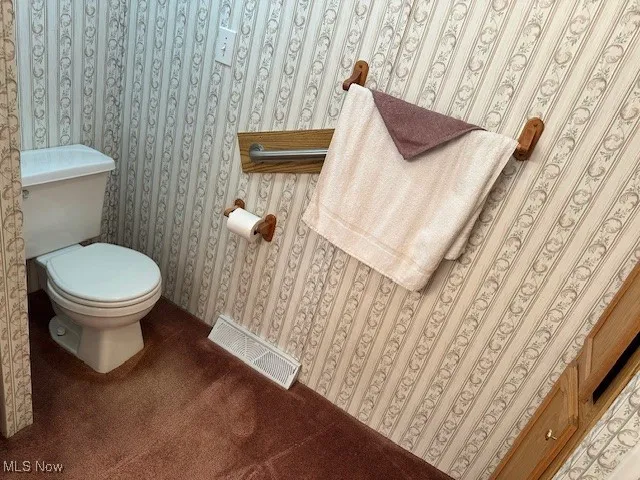 Bathroom featuring wallpapered walls and toilet