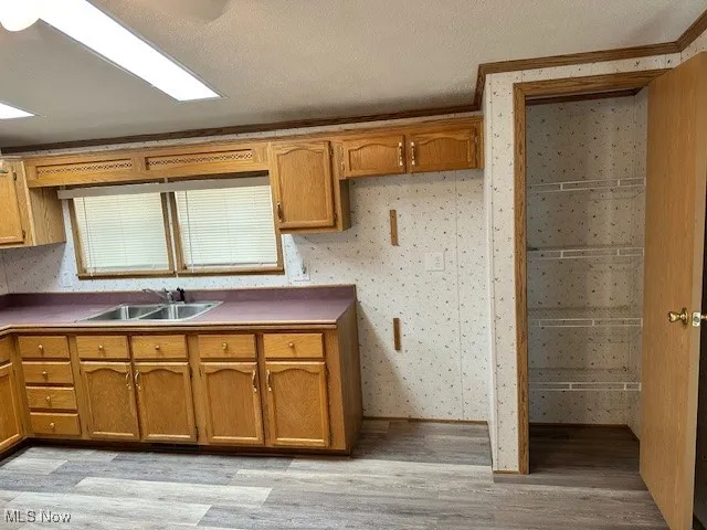 Kitchen with a sink, light wood-style flooring, and brown cabinets