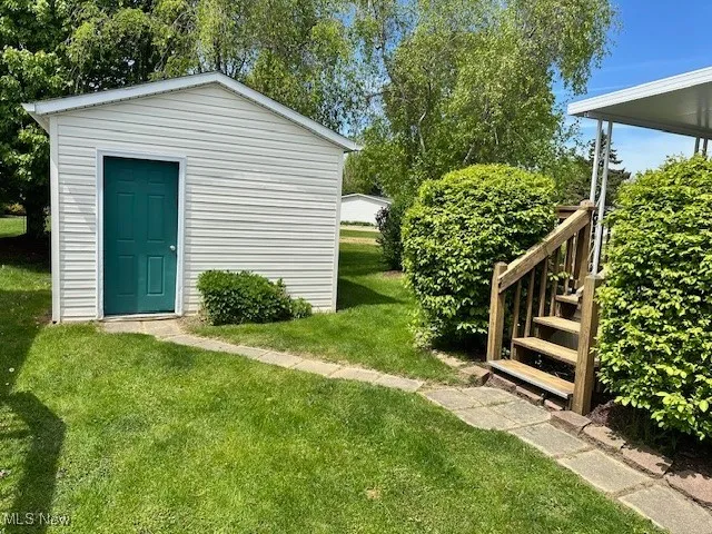View of green lawn featuring an outdoor shed and stairway to deck