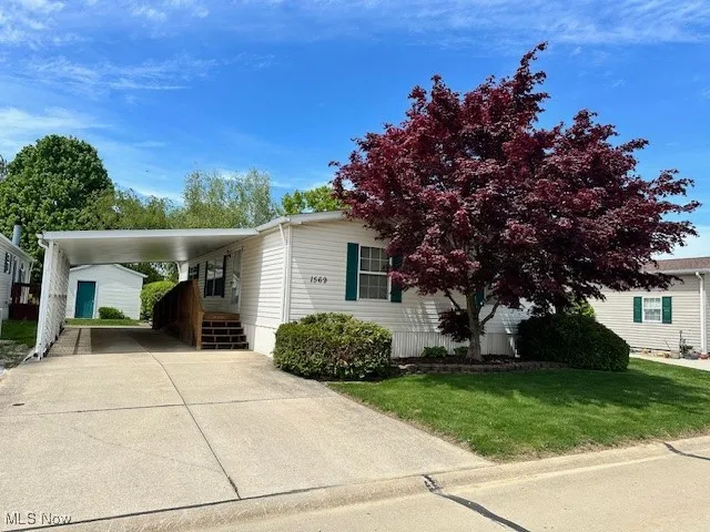 View of front of property with driveway, an attached carport, and a front lawn