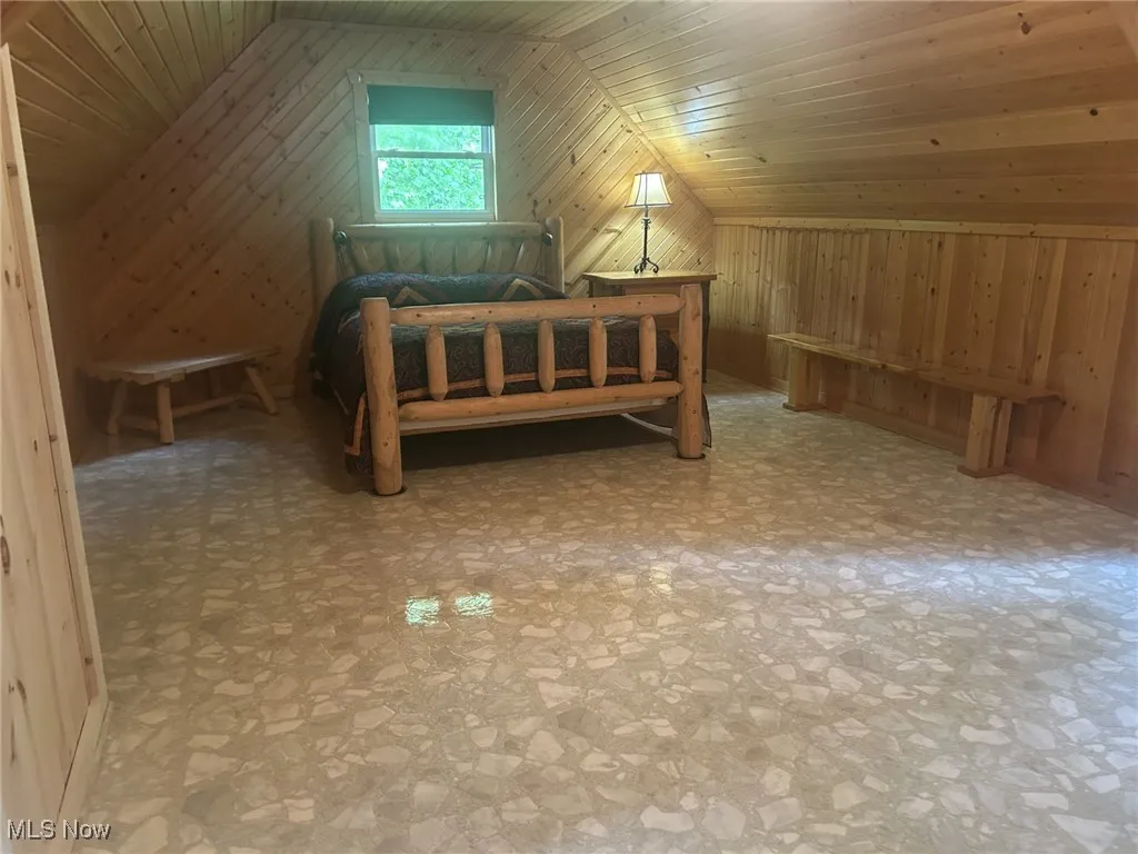 Bedroom with wooden walls, lofted ceiling, and wood ceiling