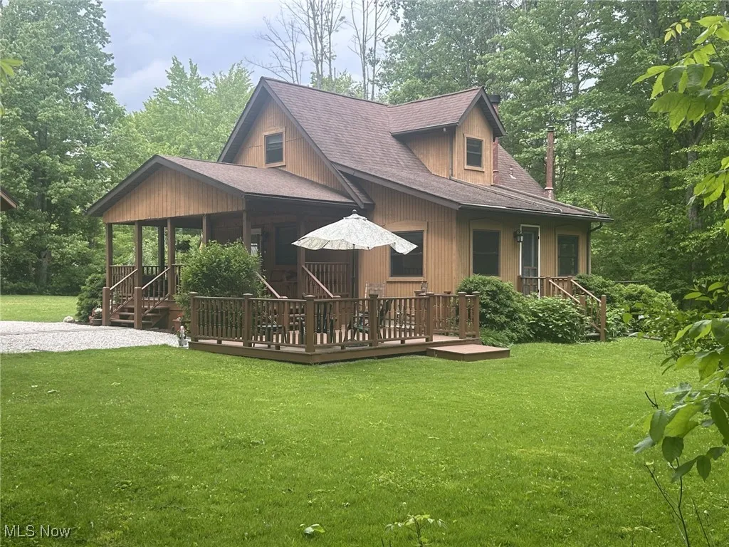 Rear view of property featuring a yard, roof with shingles, and a wooden deck