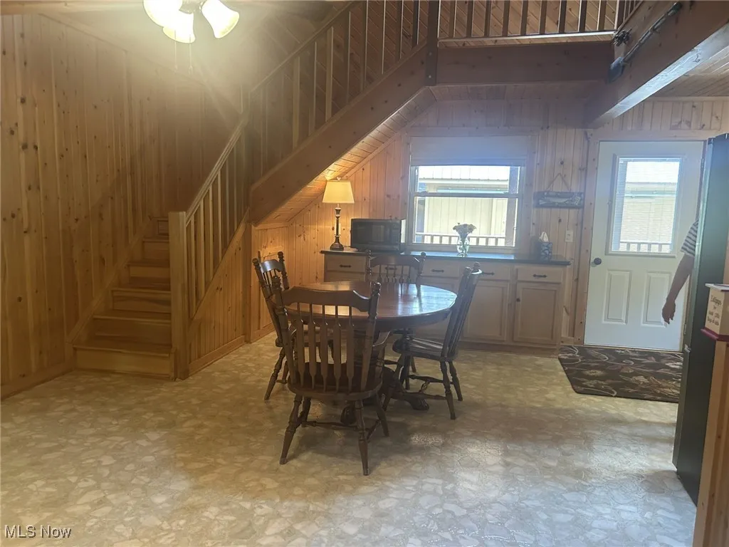 Dining space with light flooring, wooden walls, and stairway
