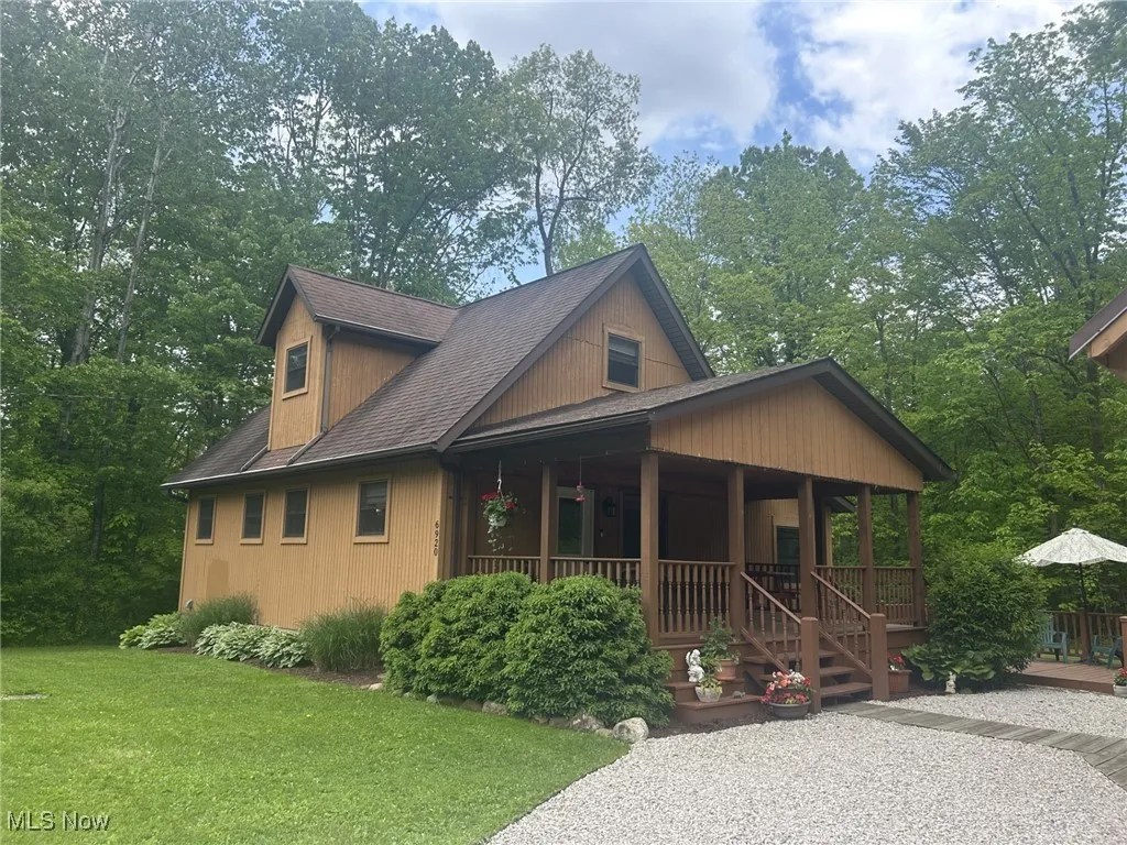 View of front facade with a porch, a front yard, and a shingled roof