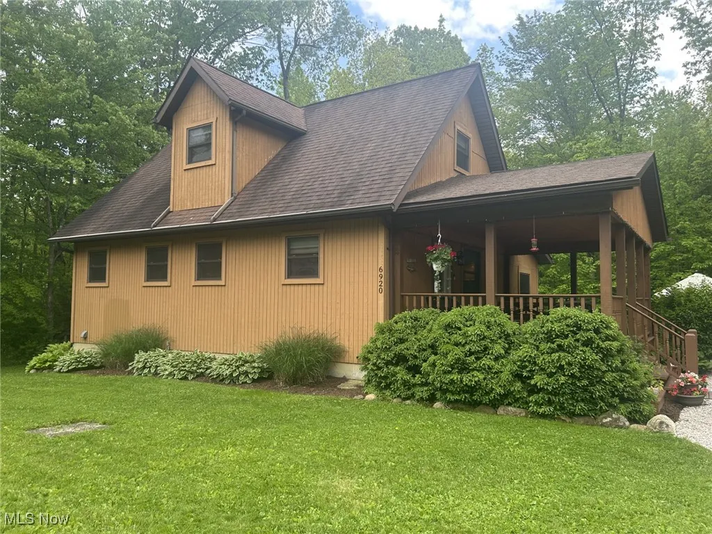 View of property exterior with a yard, a porch, and roof with shingles