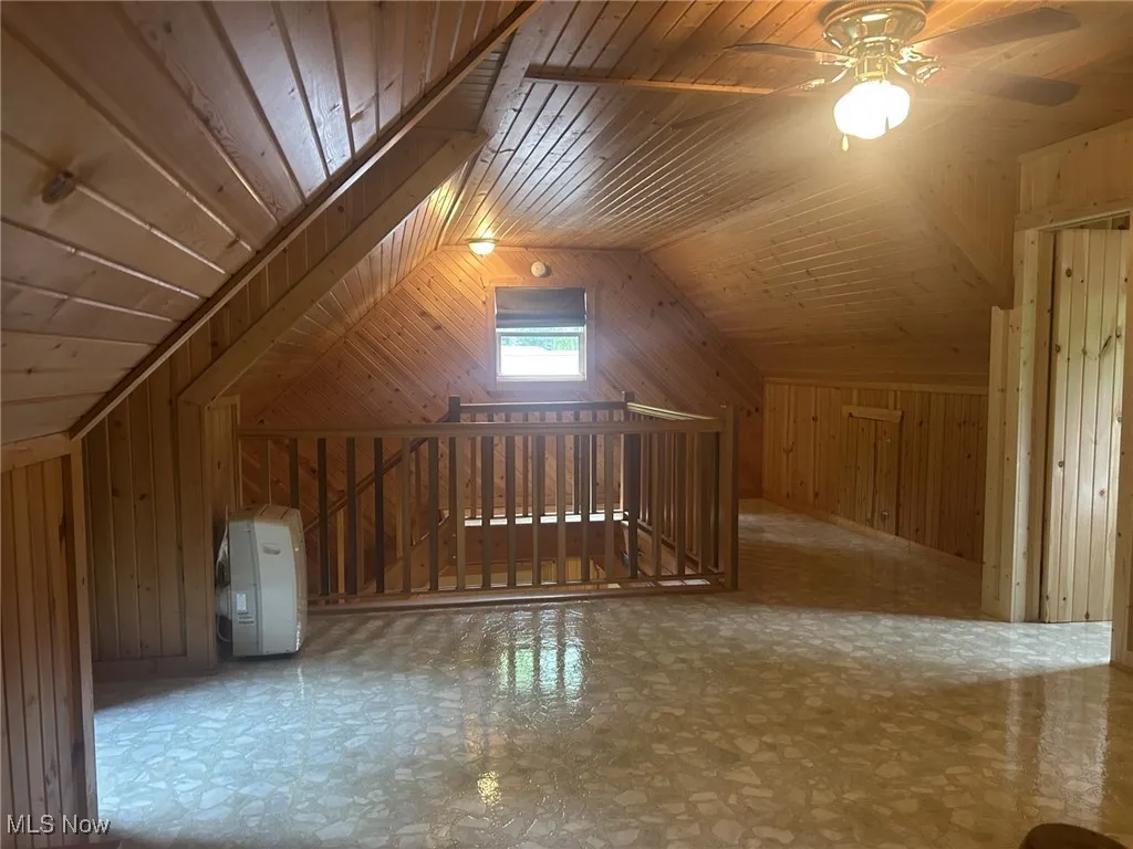 Additional living space featuring wooden walls, lofted ceiling, and ceiling fan