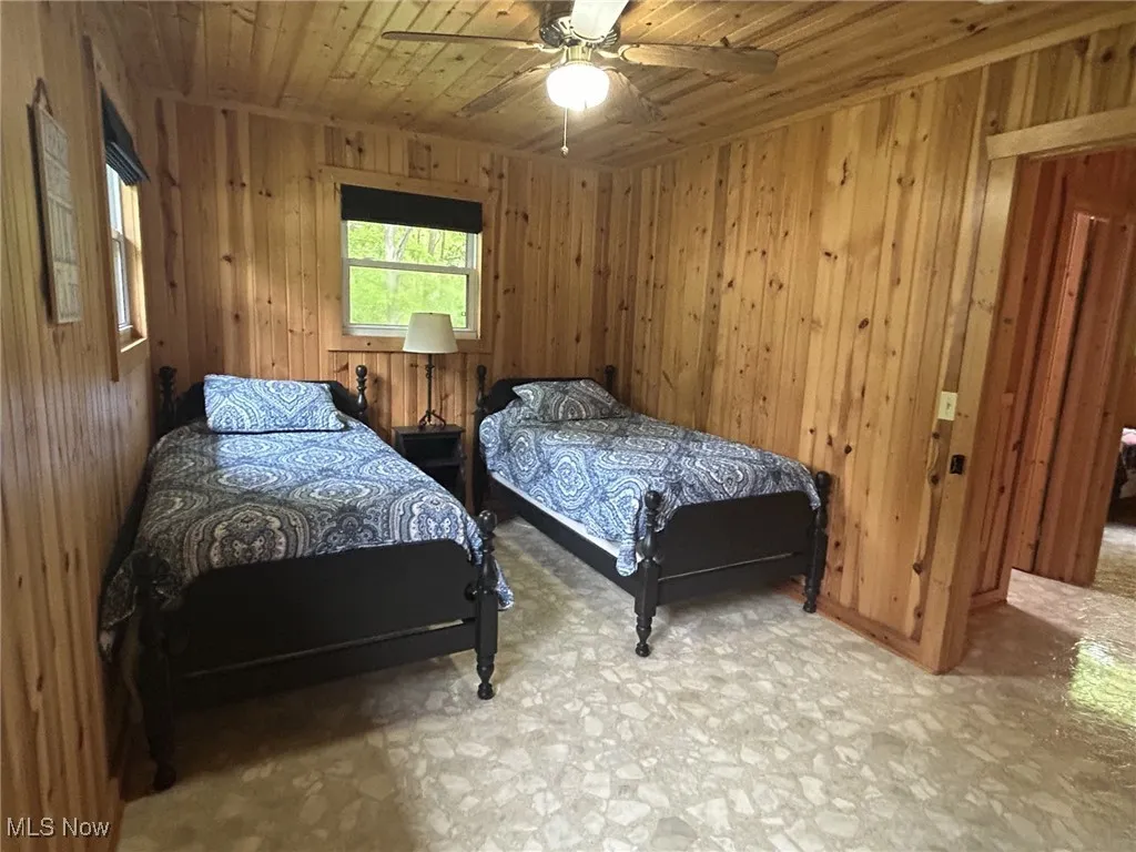 Bedroom with wooden ceiling, wooden walls, and ceiling fan