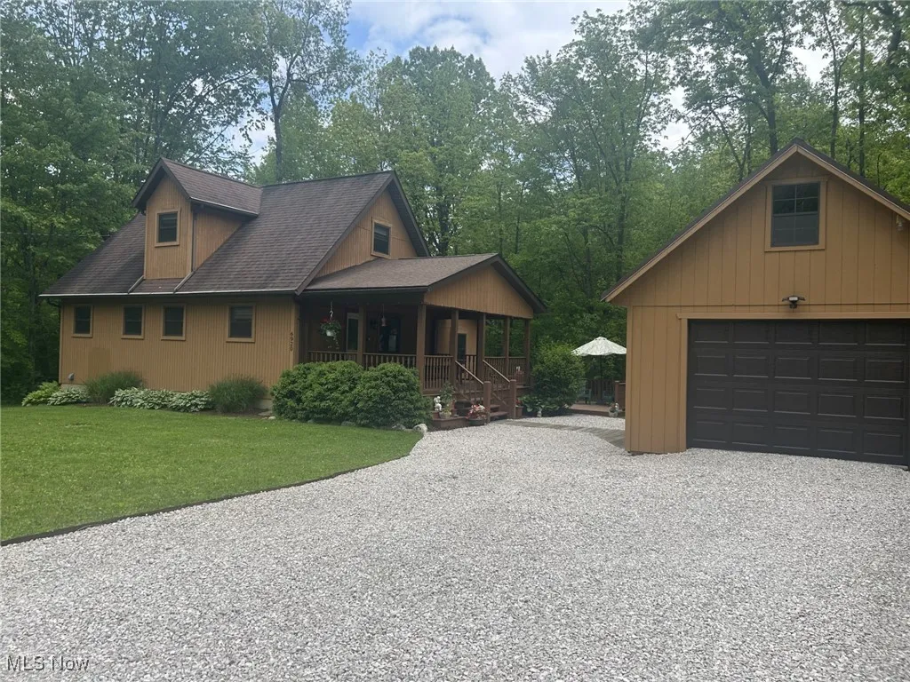 View of front of home featuring covered porch, a front lawn, a garage, and roof with shingles