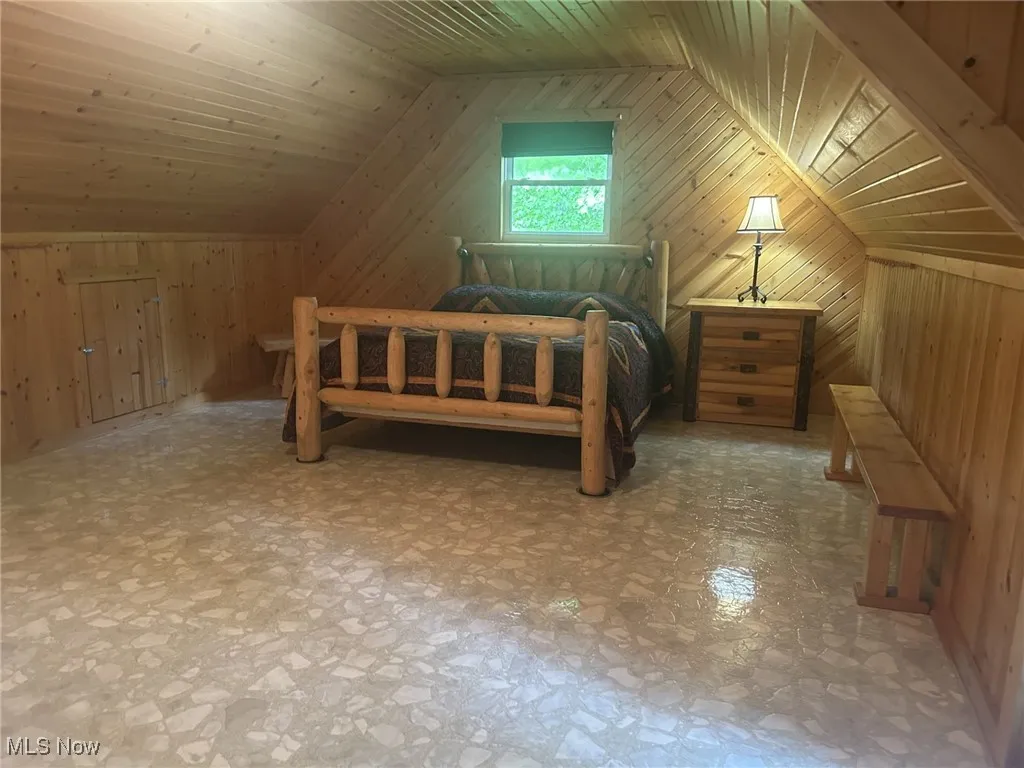 Bedroom featuring vaulted ceiling, wooden walls, and wooden ceiling