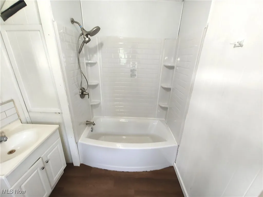 Bathroom featuring wood finished floors, vanity, and bathing tub / shower combination