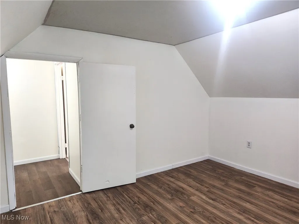 Additional living space with vaulted ceiling, wood finished floors, and baseboards