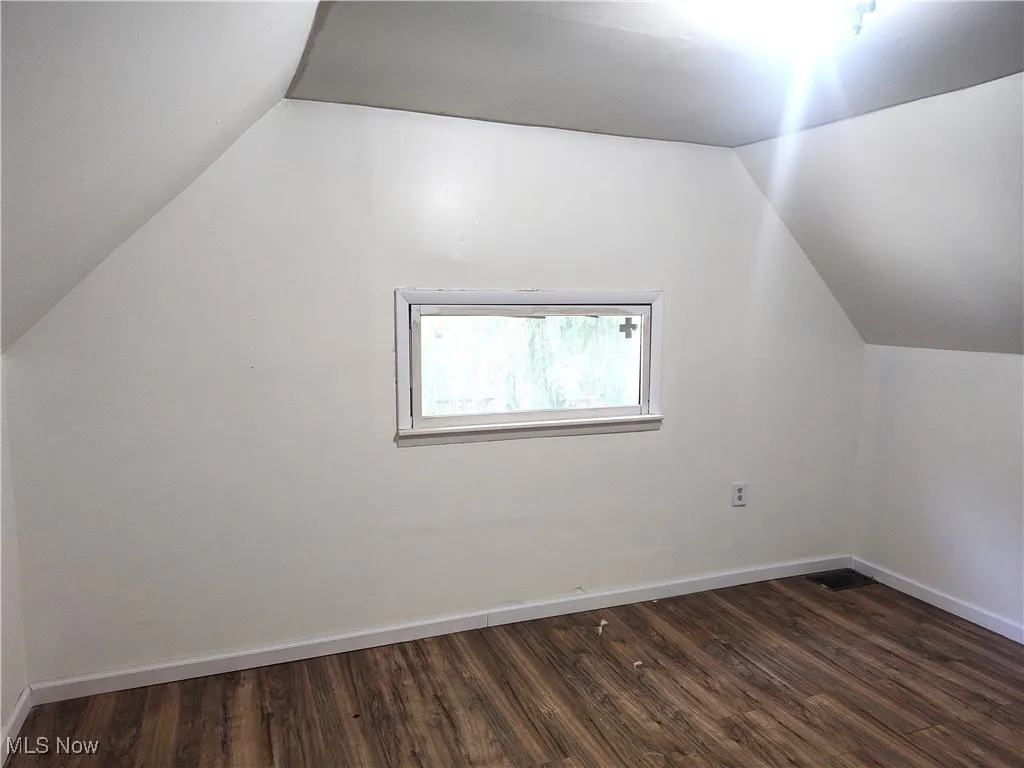 Bonus room featuring vaulted ceiling, dark wood-style floors, and baseboards