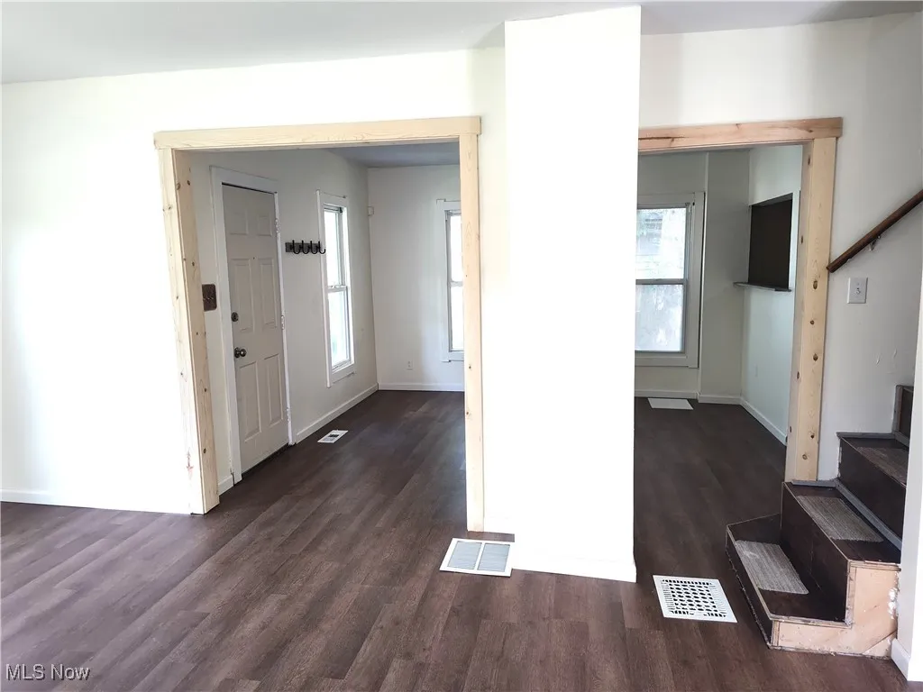 Entryway featuring stairs, dark wood-type flooring, healthy amount of natural light, and baseboards