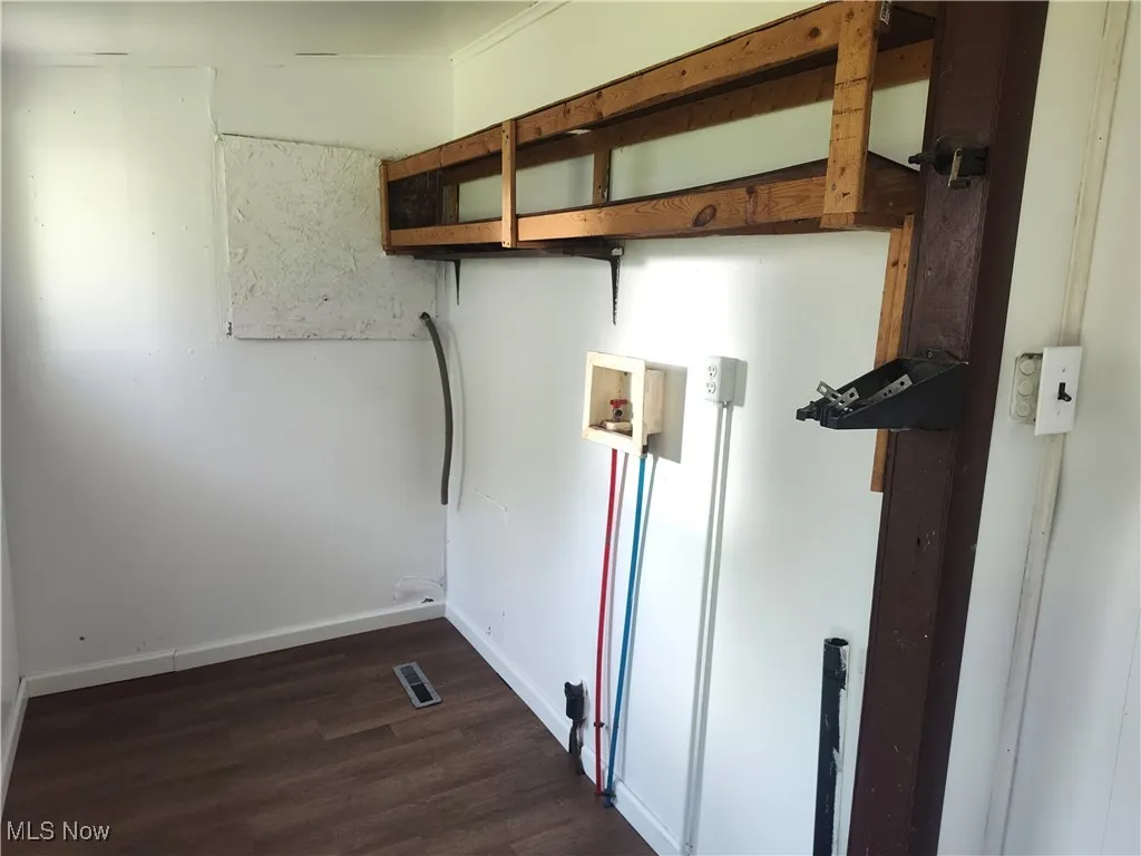 Washroom with washer hookup, dark wood finished floors, and baseboards