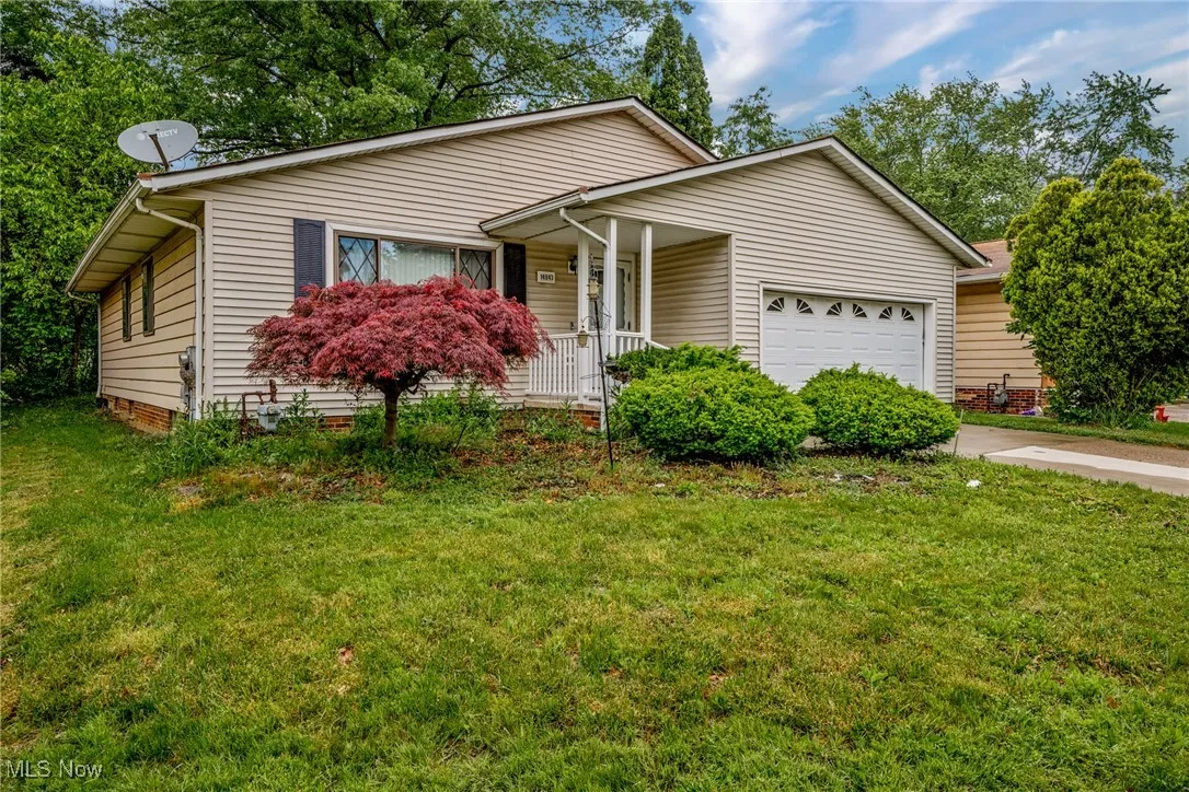 Single story home featuring an attached garage, a front lawn, a porch, and driveway