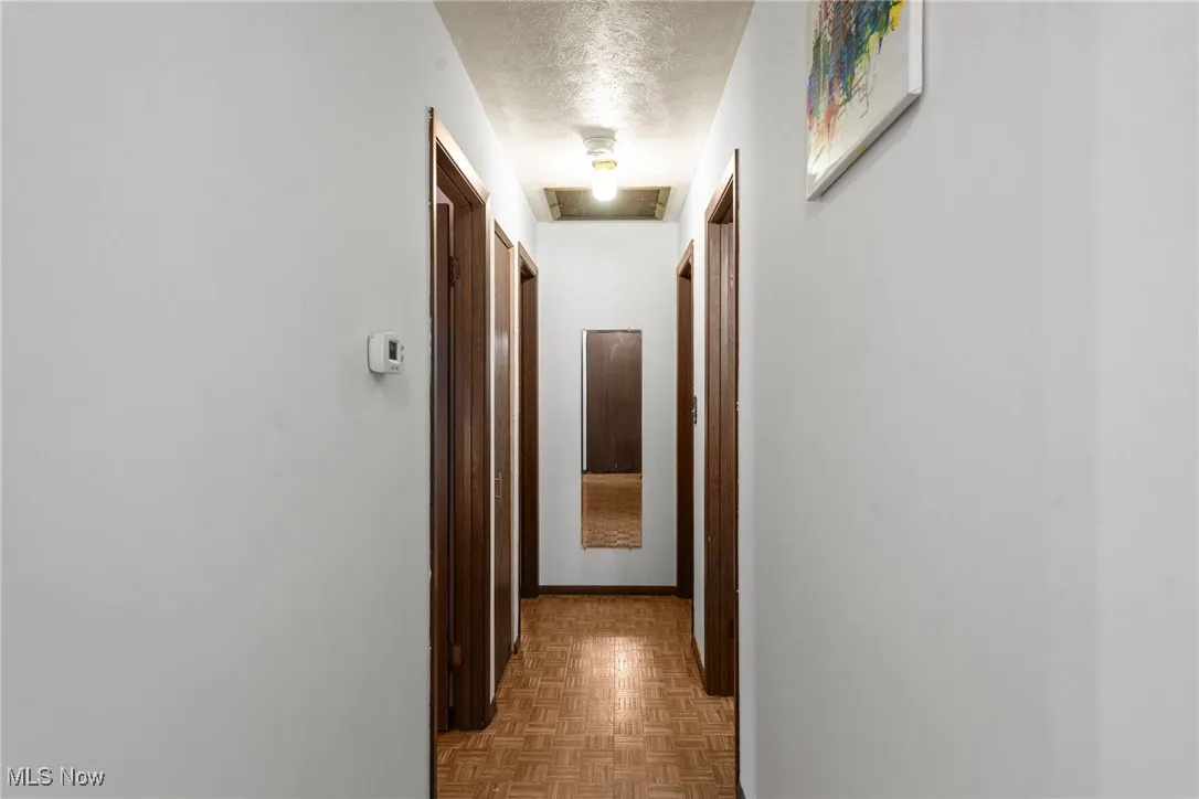 Hall featuring a textured ceiling and baseboards