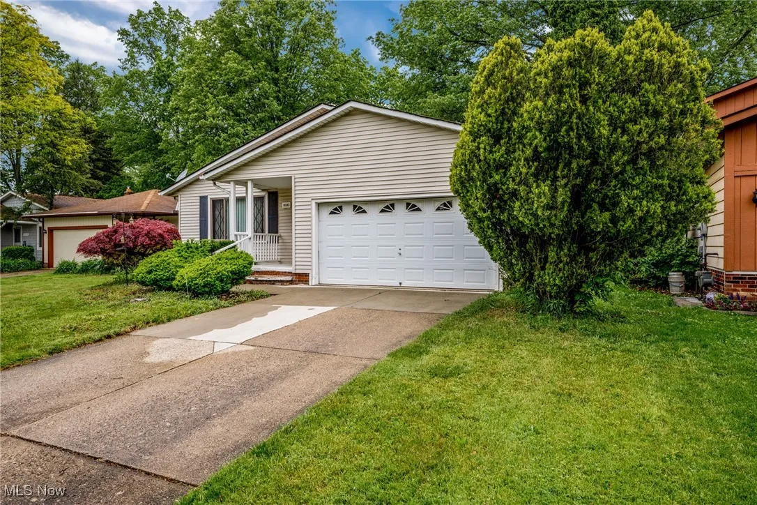 View of front facade featuring a front lawn, concrete driveway, and a garage