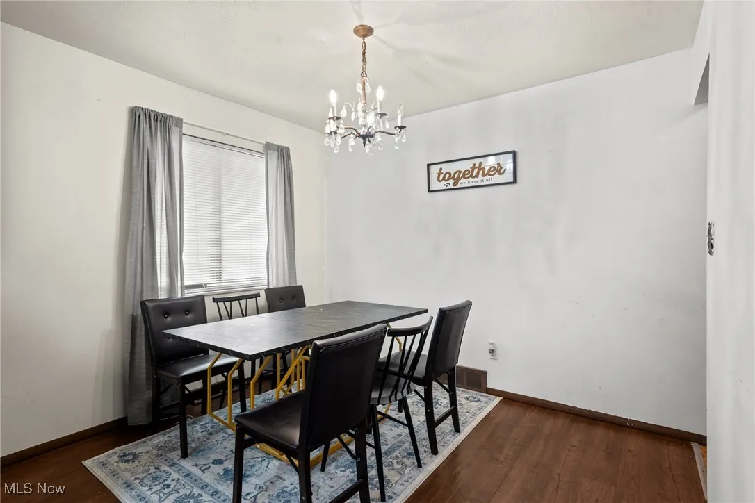 Dining area with a chandelier, dark wood-style floors, and baseboards
