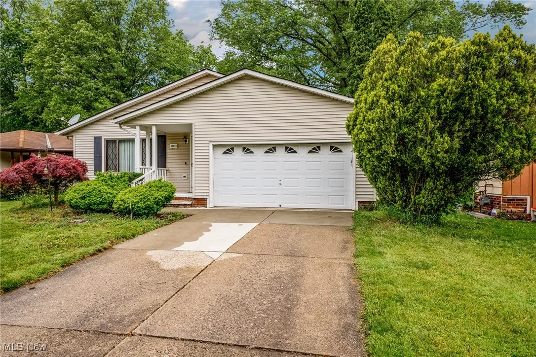 View of front facade featuring a front yard, concrete driveway, and an attached garage