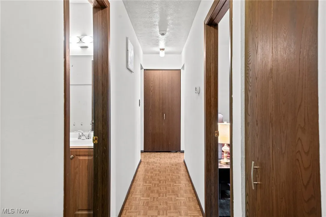 Hallway featuring a textured ceiling, baseboards, and a sink