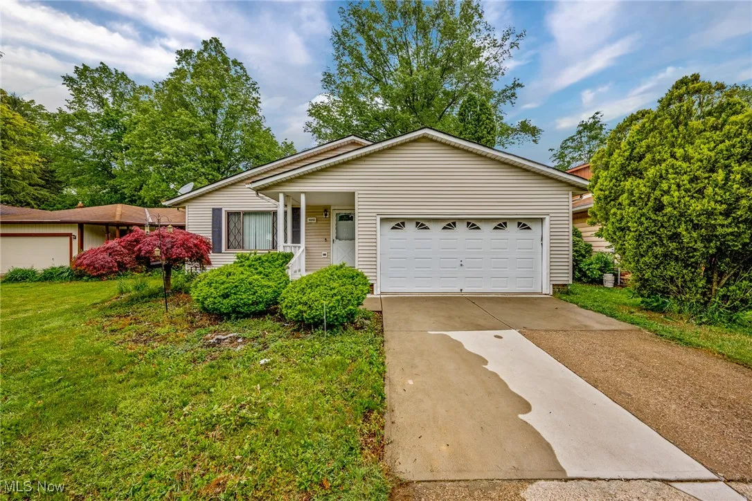 Ranch-style home featuring a garage, a front lawn, and driveway