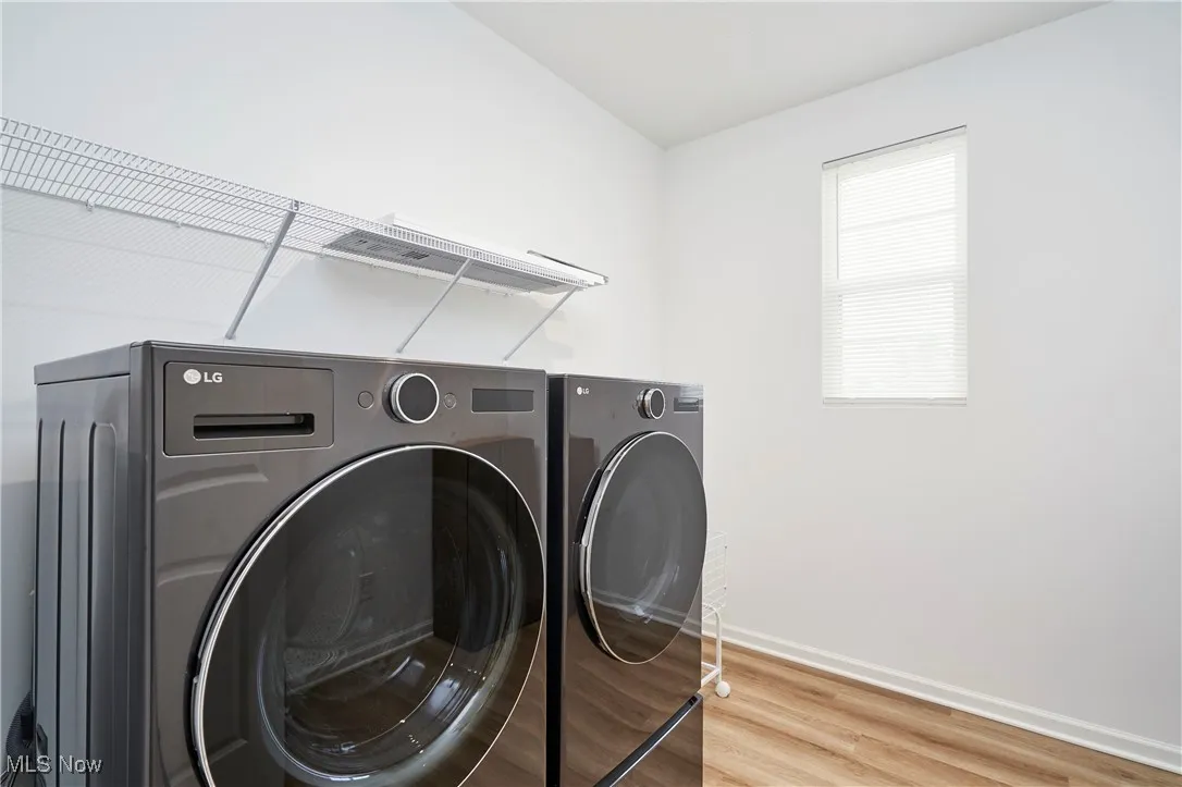 Laundry room with washer and clothes dryer, light wood-style floors, and baseboards