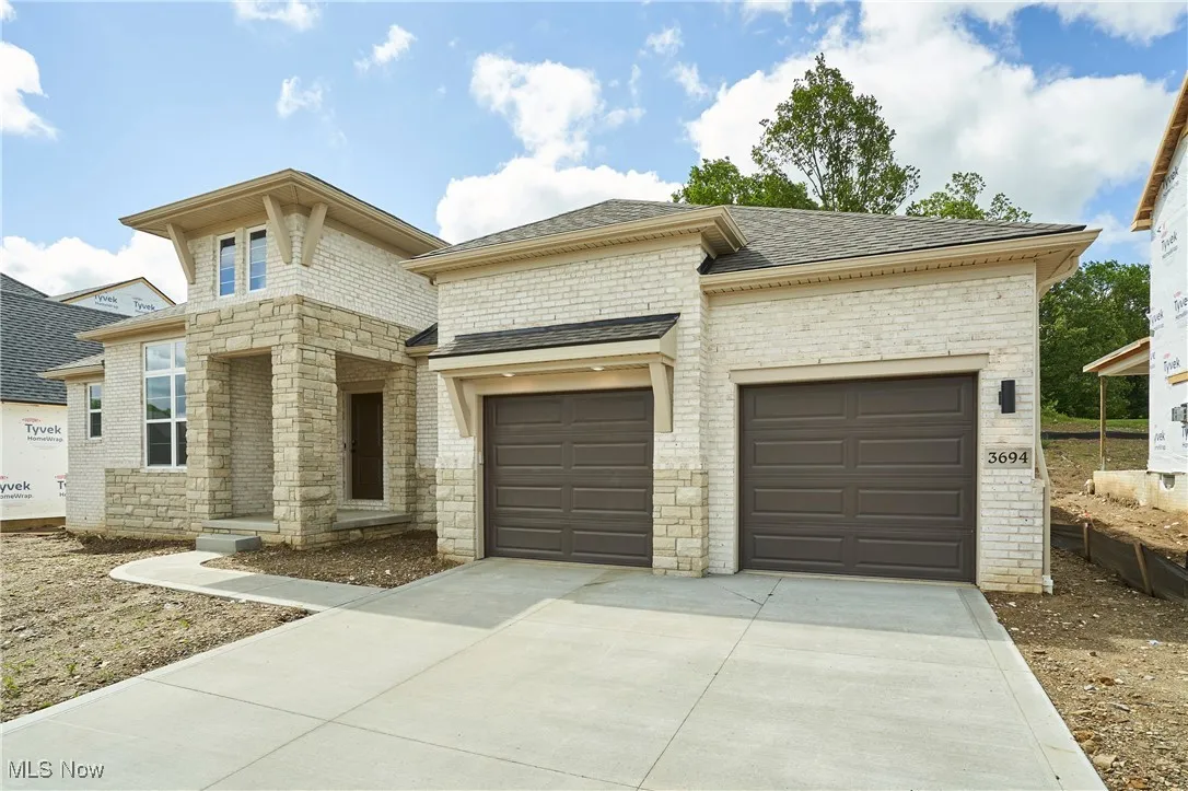 View of front of property with driveway, an attached garage, roof with shingles, and brick siding