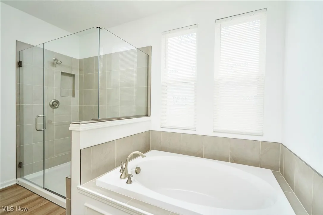 Bathroom with a bath, a stall shower, and wood finished floors