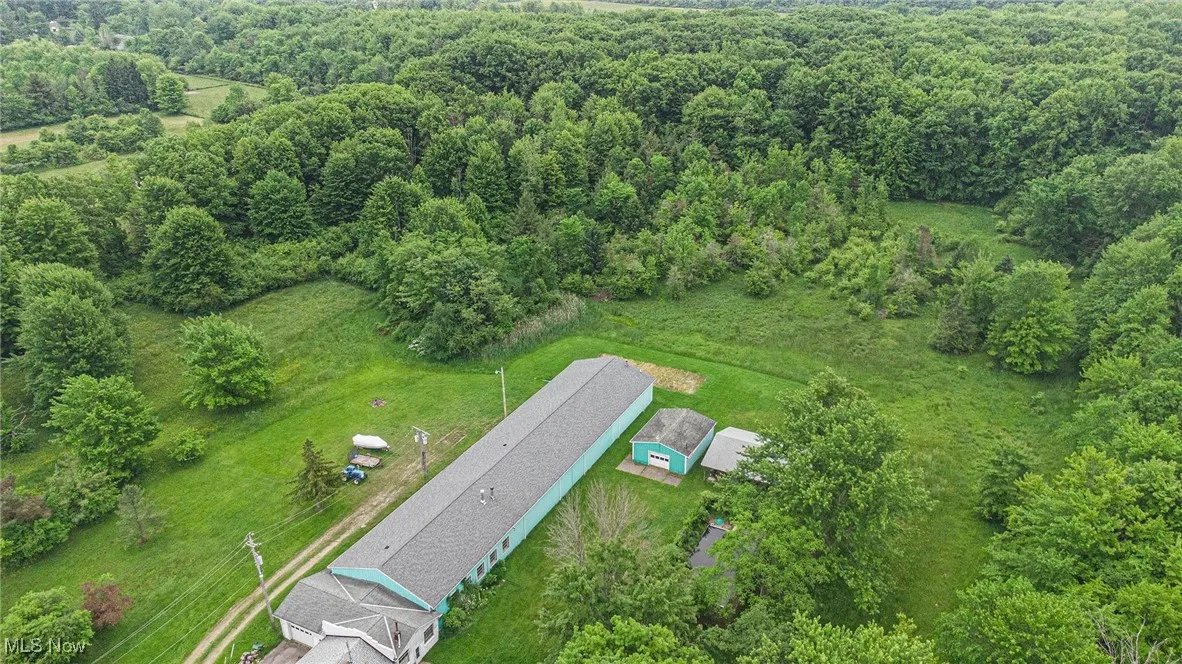 Aerial view of property and surrounding area featuring a heavily wooded area