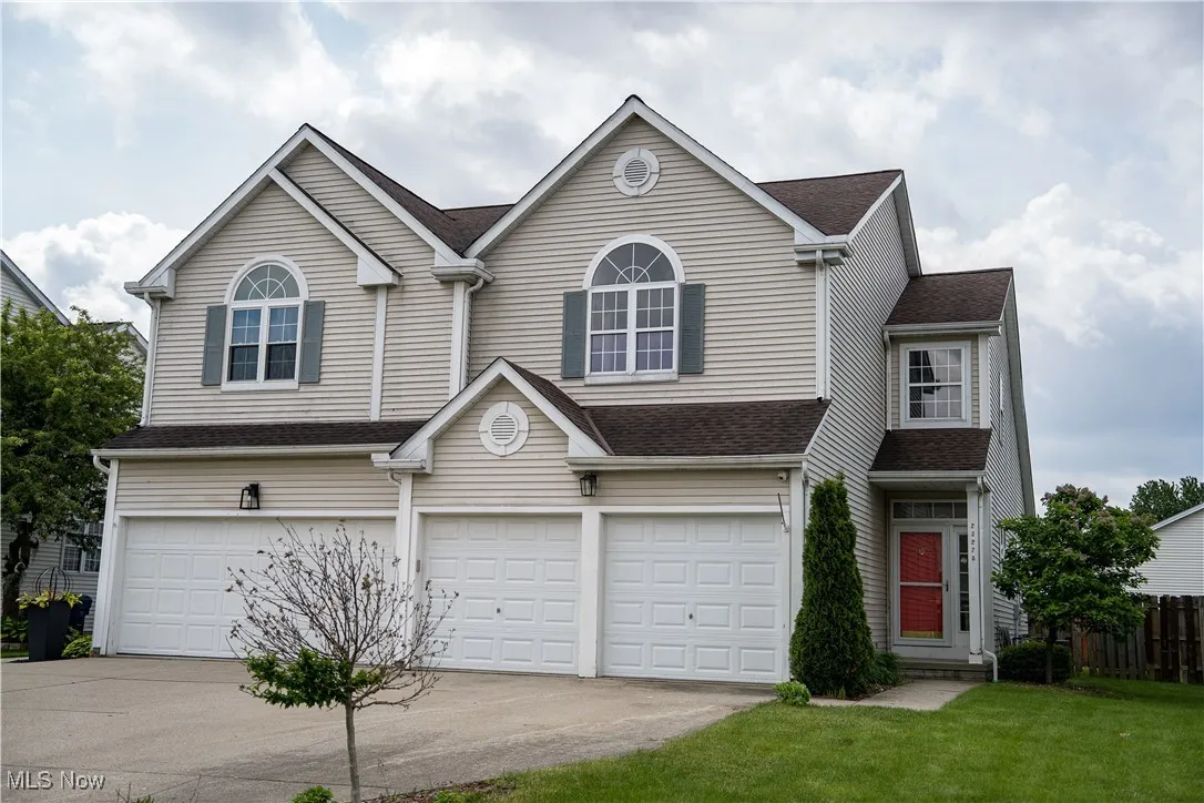 Traditional home with a garage, concrete driveway, and a shingled roof