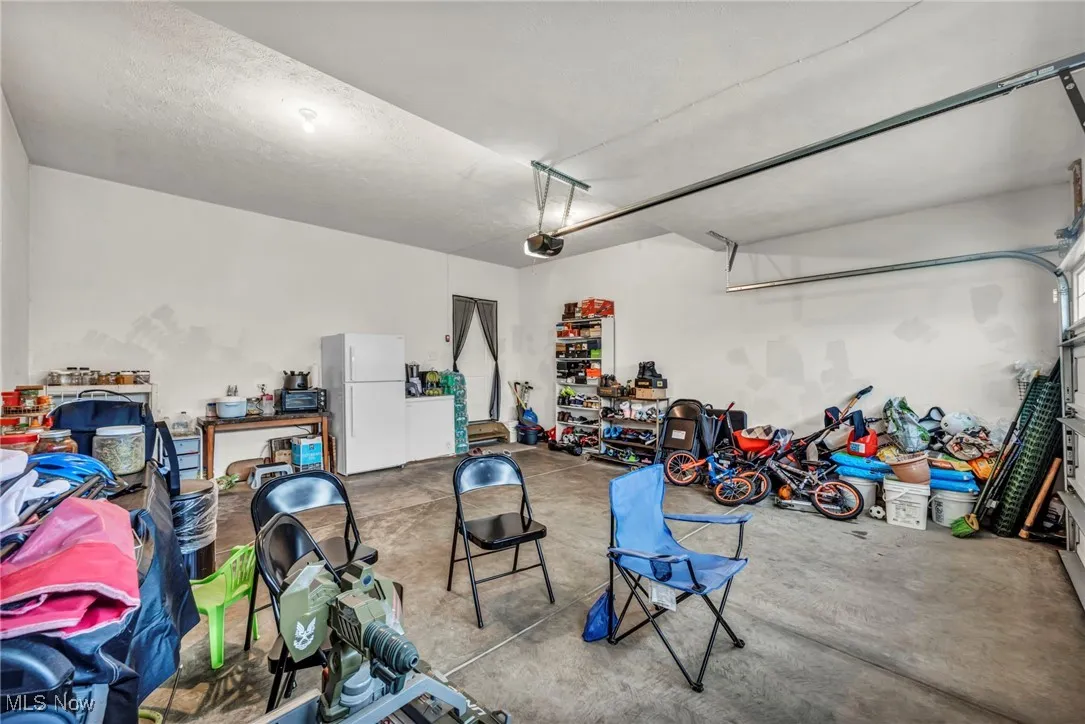 Garage with freestanding refrigerator and a garage door opener