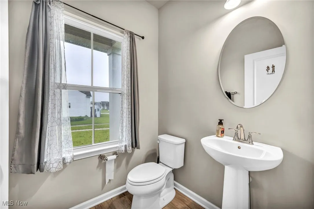 Bathroom with wood finished floors, baseboards, and toilet