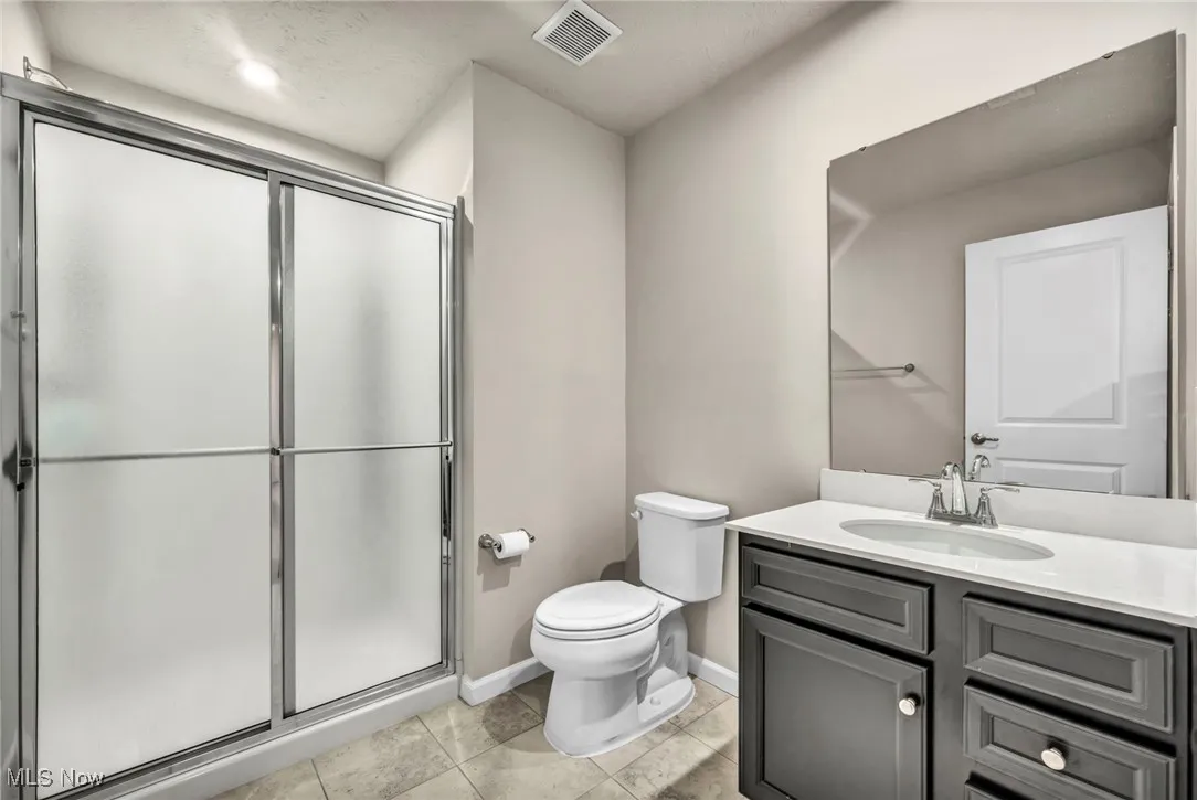 Bathroom featuring vanity, toilet, a shower stall, and baseboards