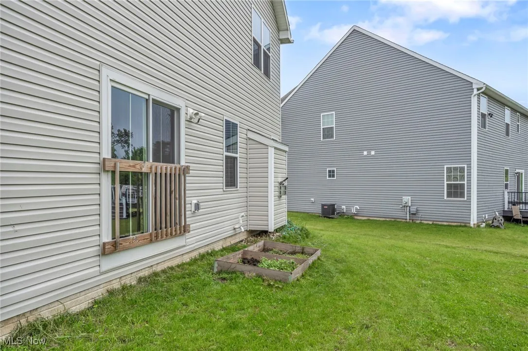 View of home's exterior with a lawn, central AC, and a garden