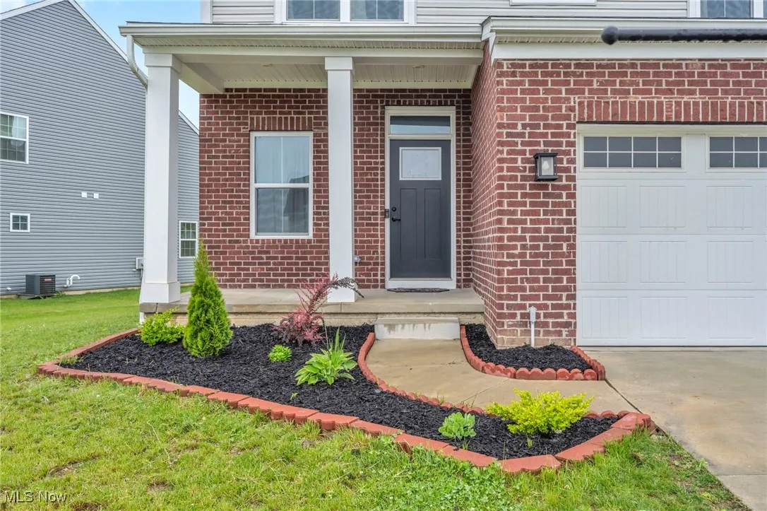 Entrance to property with brick siding, driveway, and an attached garage