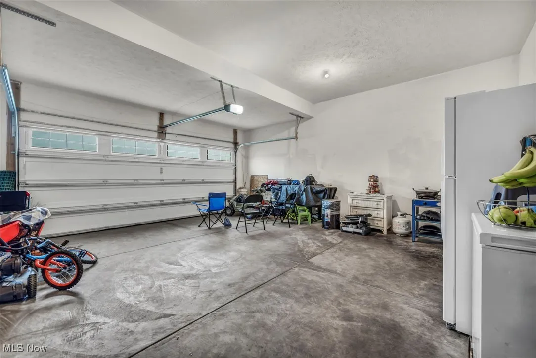 Garage with a garage door opener and freestanding refrigerator