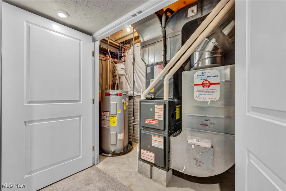 Utility room featuring electric water heater and heating unit
