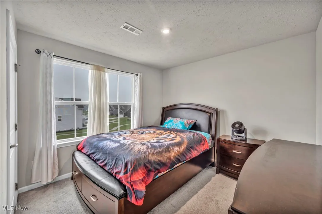 Bedroom with light carpet, baseboards, and a textured ceiling