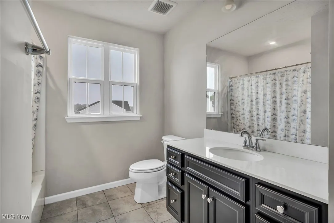 Full bathroom with vanity, toilet, baseboards, and tile patterned flooring