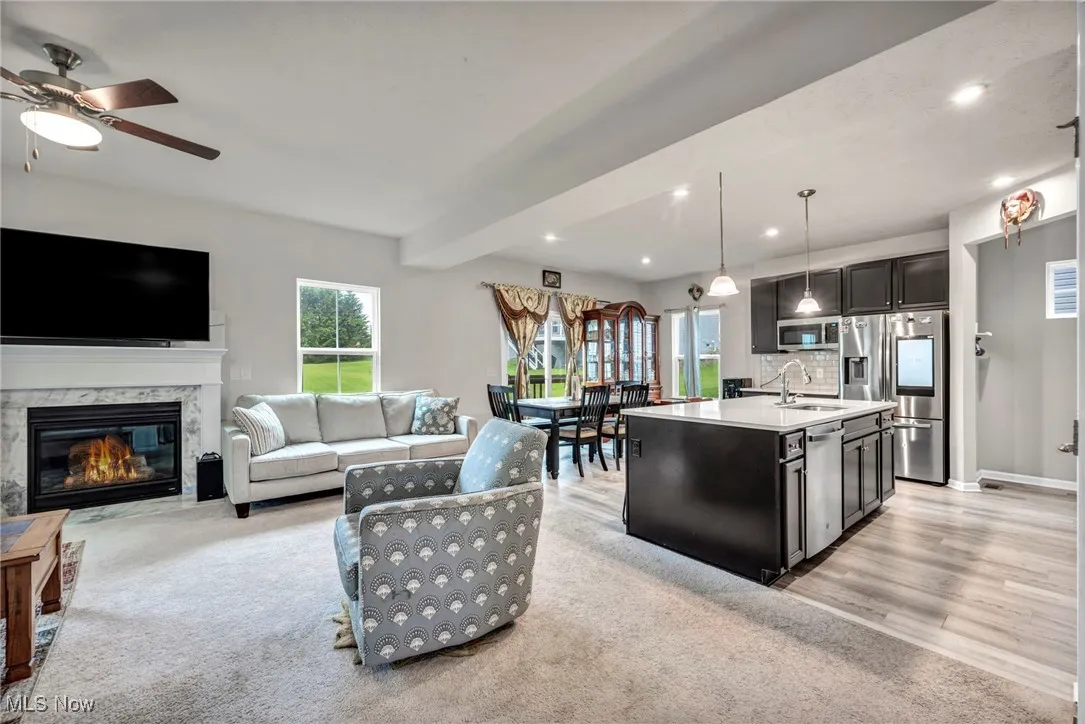 Kitchen featuring appliances with stainless steel finishes, a sink, light countertops, hanging light fixtures, and ceiling fan