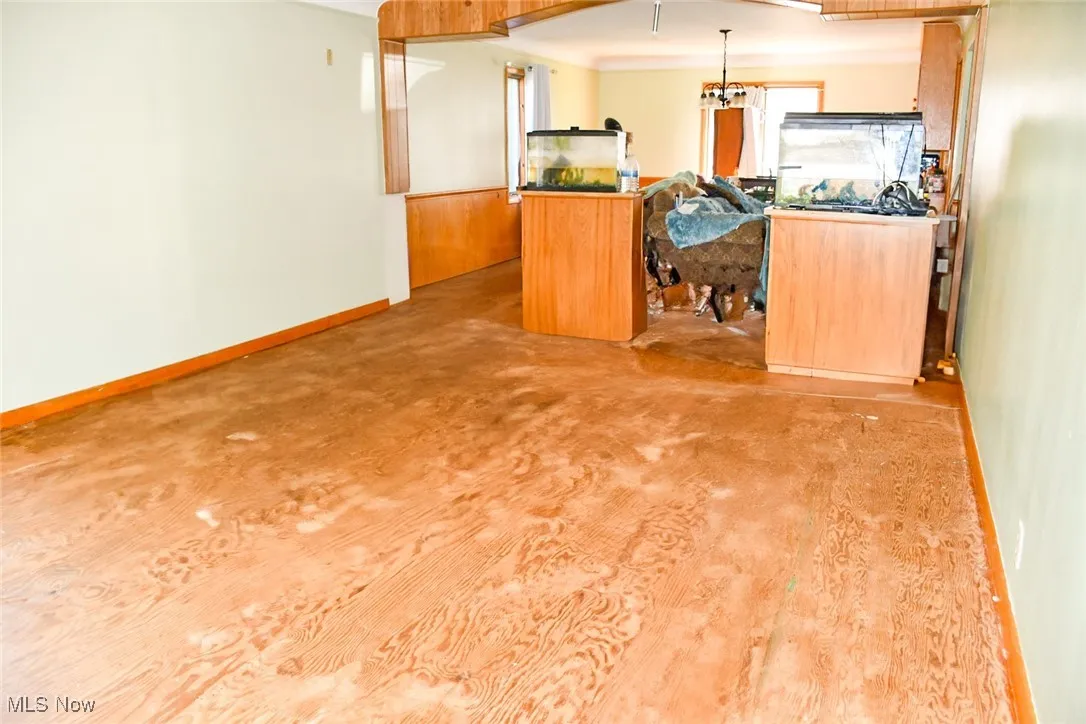 Living room with baseboards, decorative light fixtures, and brown cabinets