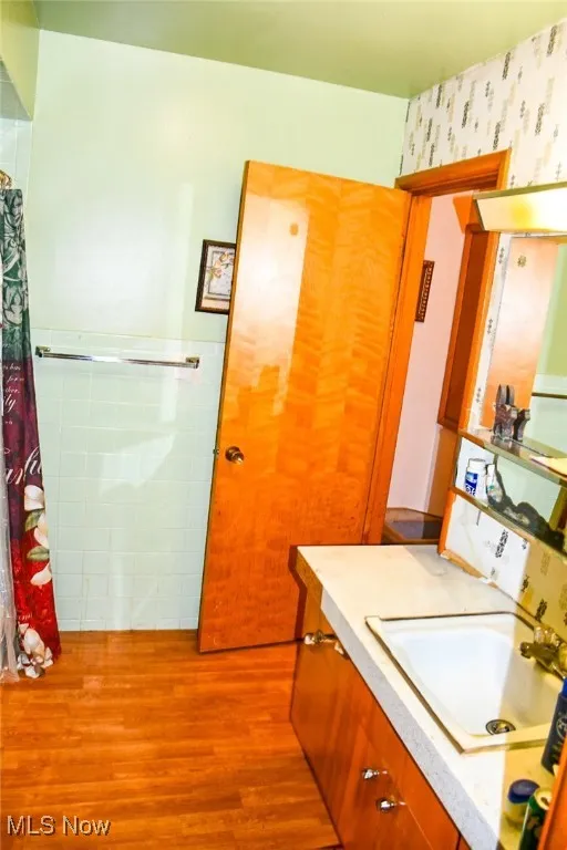 Full kithen with wood finished floors, vanity, and wallpapered walls