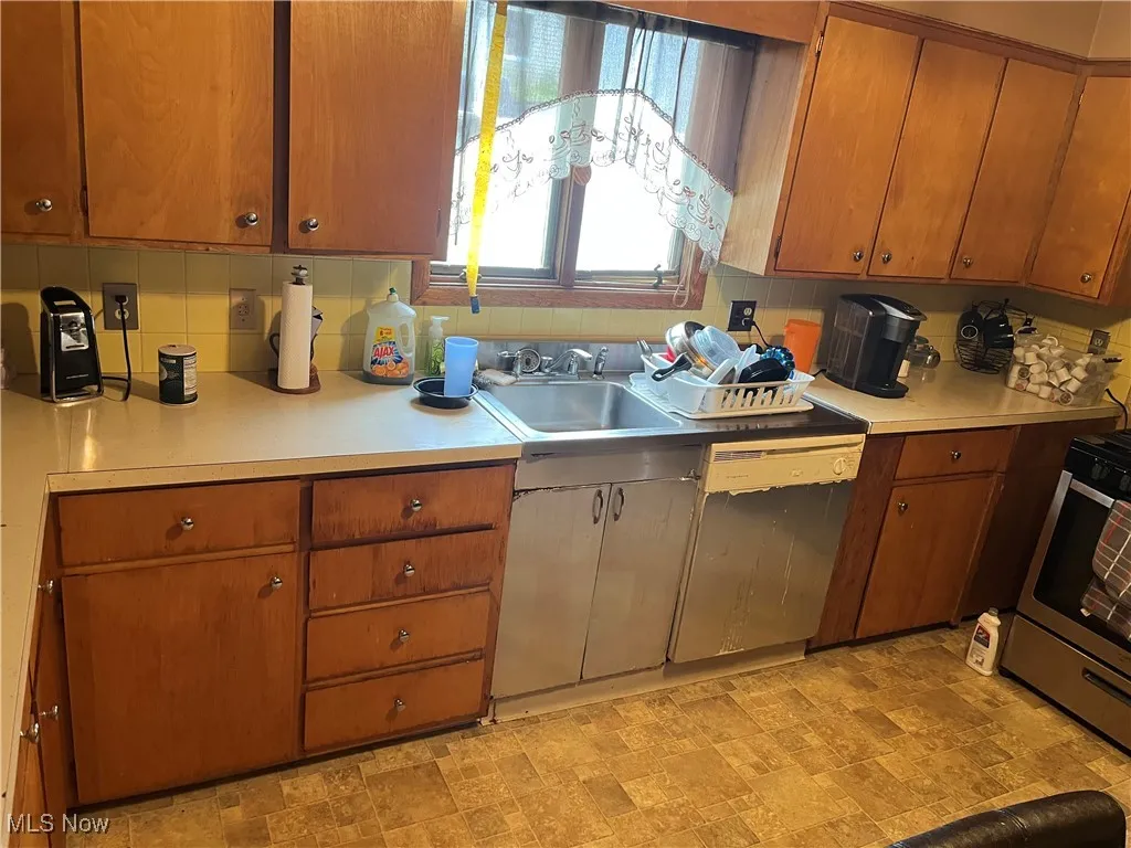 Kitchen with a sink, stainless steel range oven, light countertops, and dishwasher