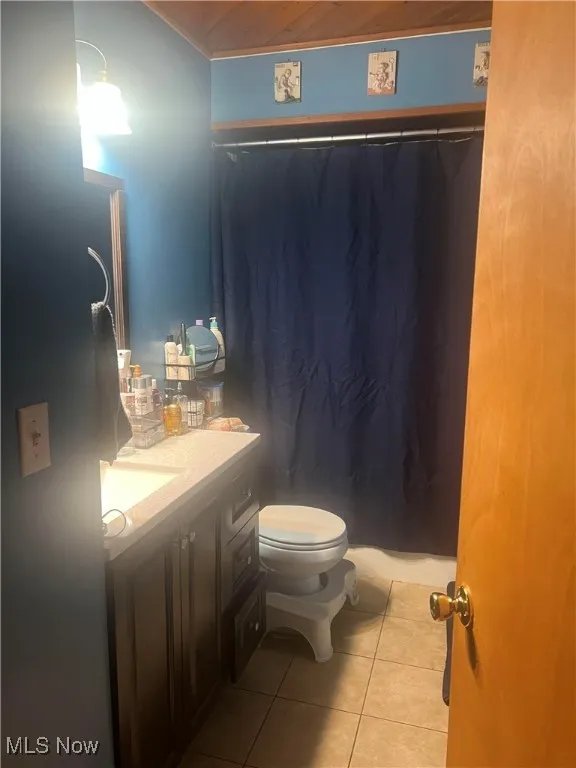 Full bathroom with vanity, toilet, tile patterned flooring, ornamental molding, and a shower with shower curtain