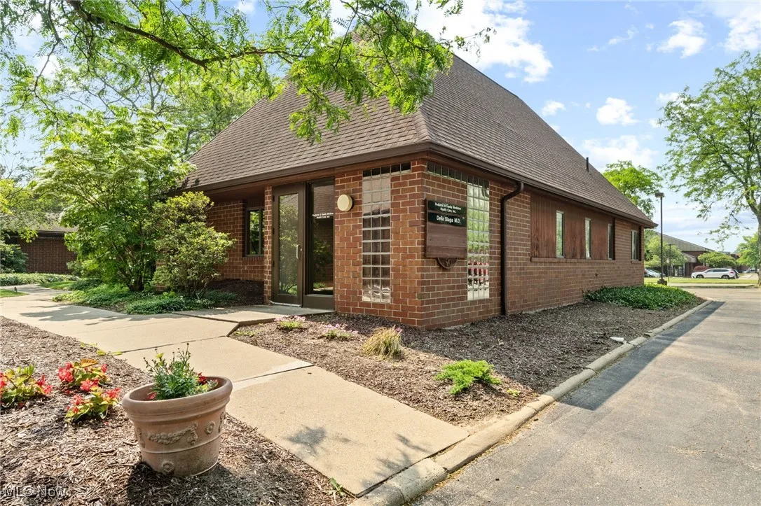 View of front facade with brick siding and roof with shingles.