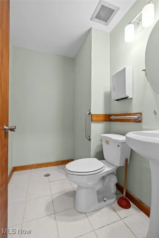Half bathroom featuring baseboards, toilet, and tile patterned floors