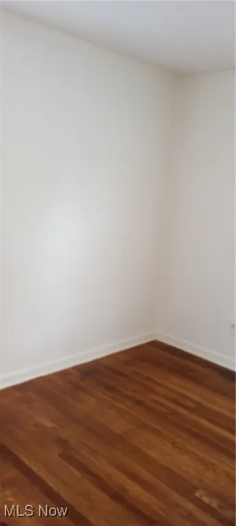 Empty room with dark wood finished floors and baseboards