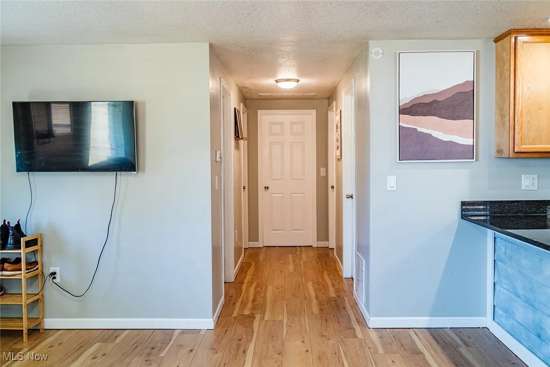 Hallway featuring a textured ceiling and light wood-style floors