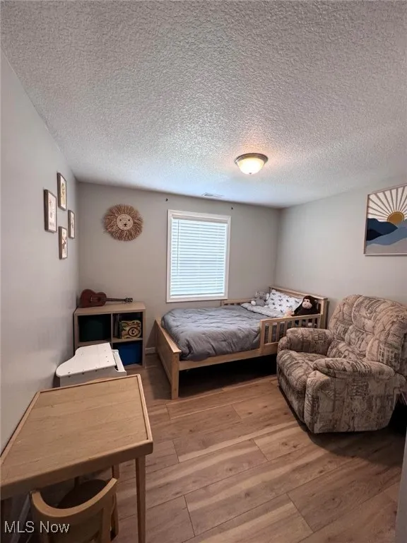 Bedroom featuring light wood-type flooring and a textured ceiling